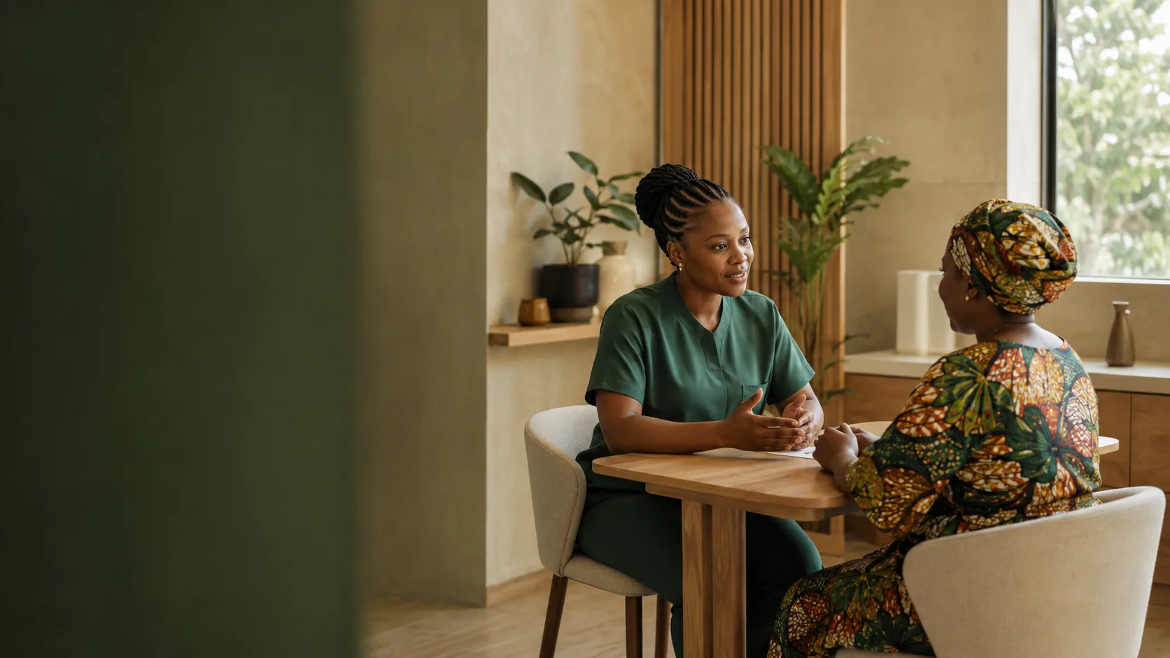 A Nigerian clinician in conversation with a patient in a calm, bright care setting